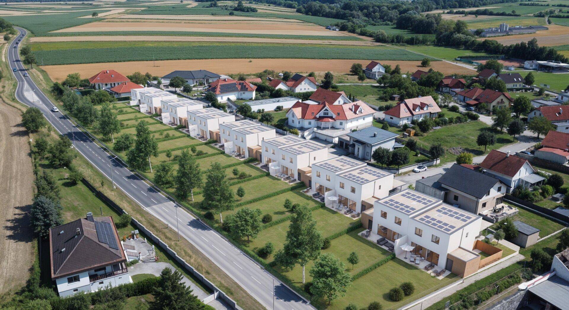 Luftaufnahme einer modernen Reihenhaussiedlung in ländlicher Umgebung mit Photovoltaikanlagen auf den Dächern.