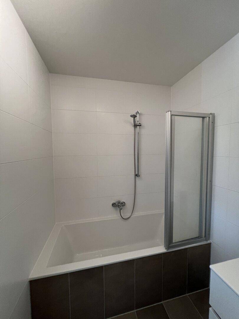 Badezimmer mit Badewanne und Duschabtrennung in modernem Design.