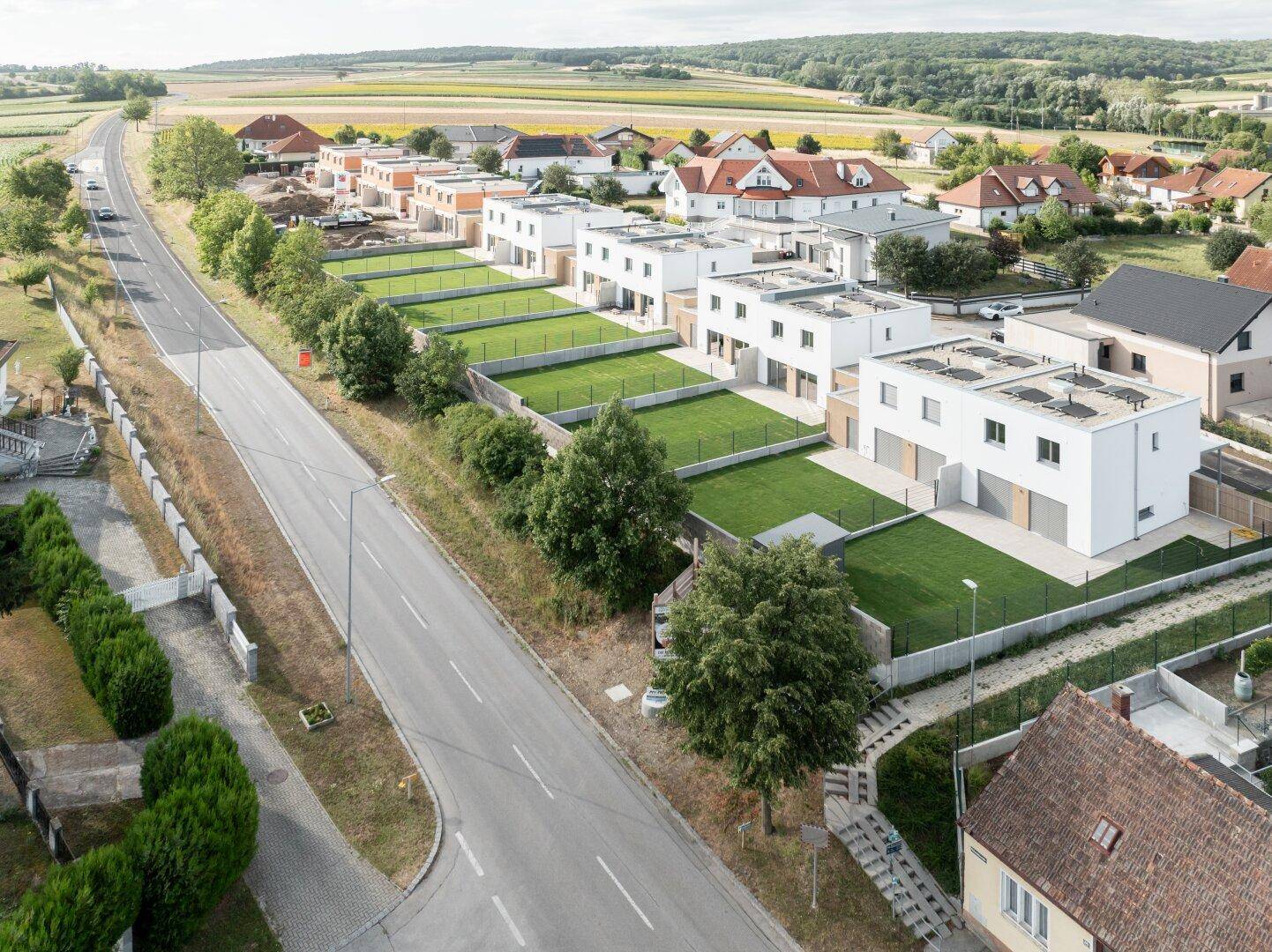 Luftaufnahme einer neuen Wohnsiedlung mit modernen Häusern und weitläufigen Grünflächen.