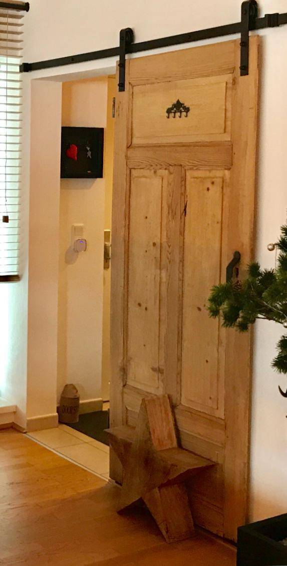 Rustikale Holzschiebetür im Scheunentor-Stil in einem hellen Flurbereich.