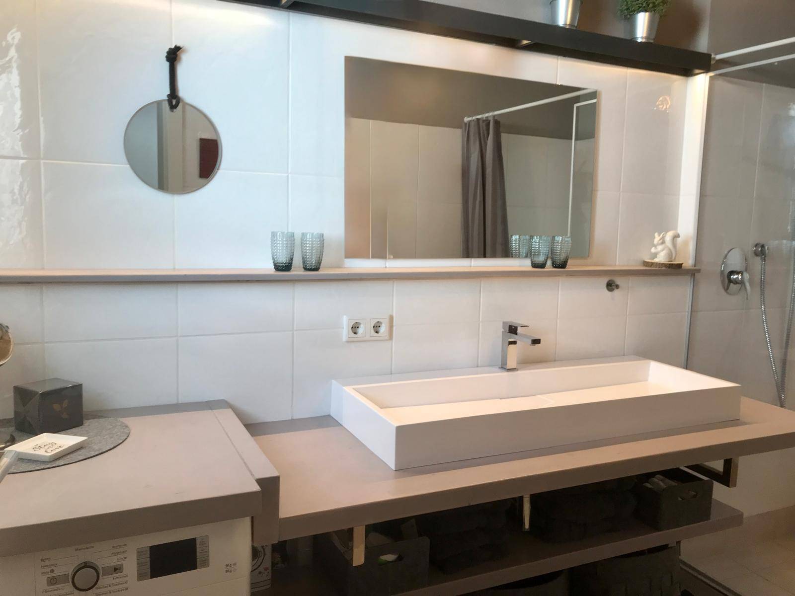 Modernes Badezimmer mit rechteckigem Aufsatzwaschbecken, großem Spiegel und weißen Fliesen.