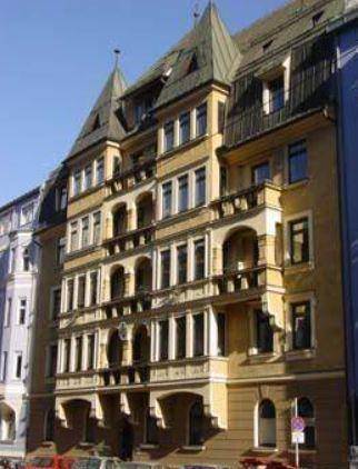 Historisches Mehrfamilienhaus mit aufwendiger Fassade, vielen Fenstern und Balkonen in städtischer Umgebung.
