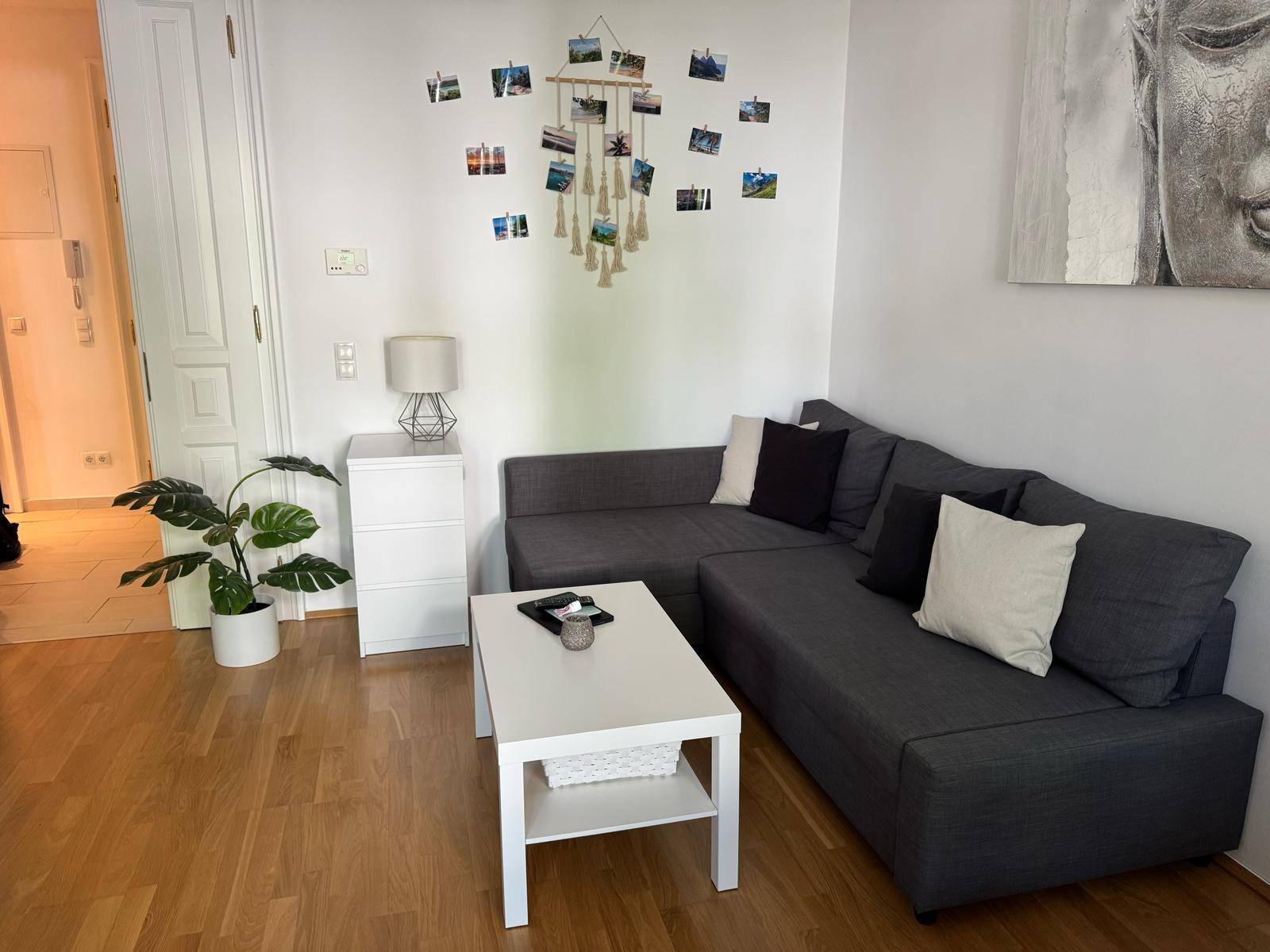 Gemütliches Wohnzimmer mit dunklem Ecksofa, weißem Couchtisch und Holzboden.