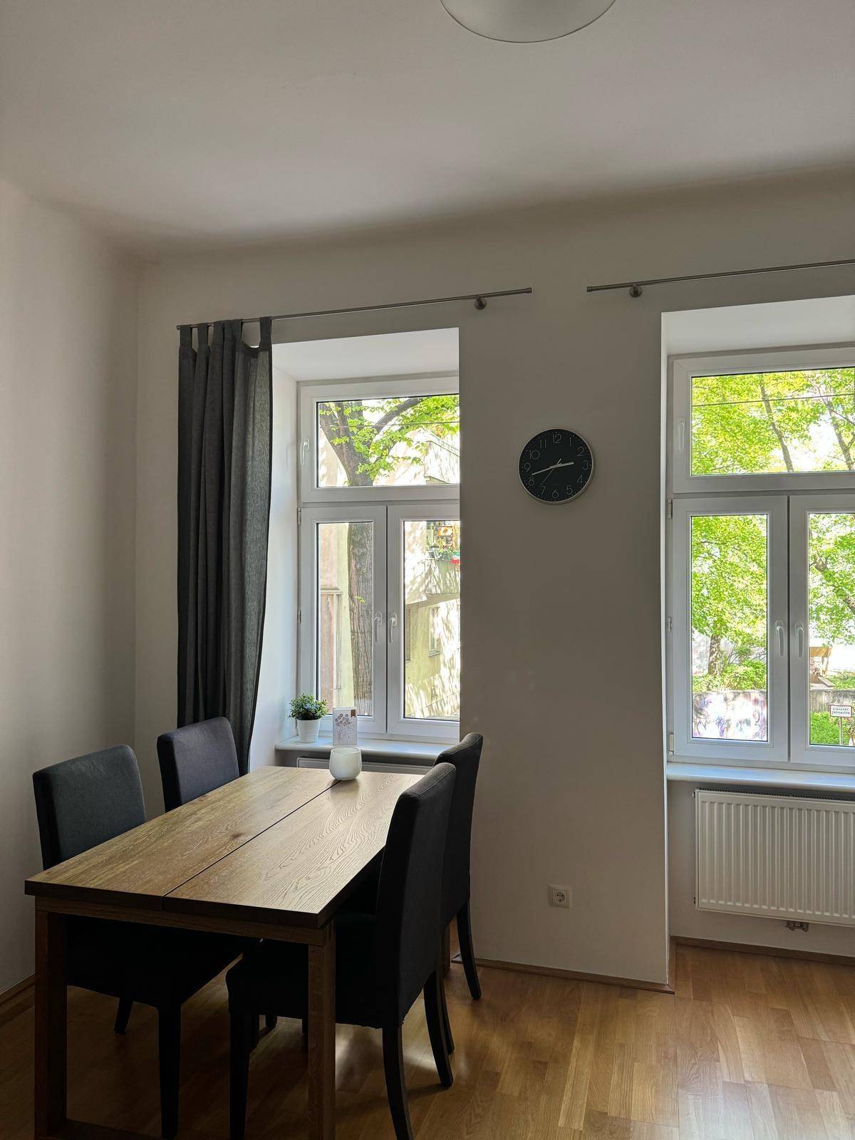 Heller Essbereich mit Holztisch und Stühlen, großen Fenstern und Blick ins Grüne.