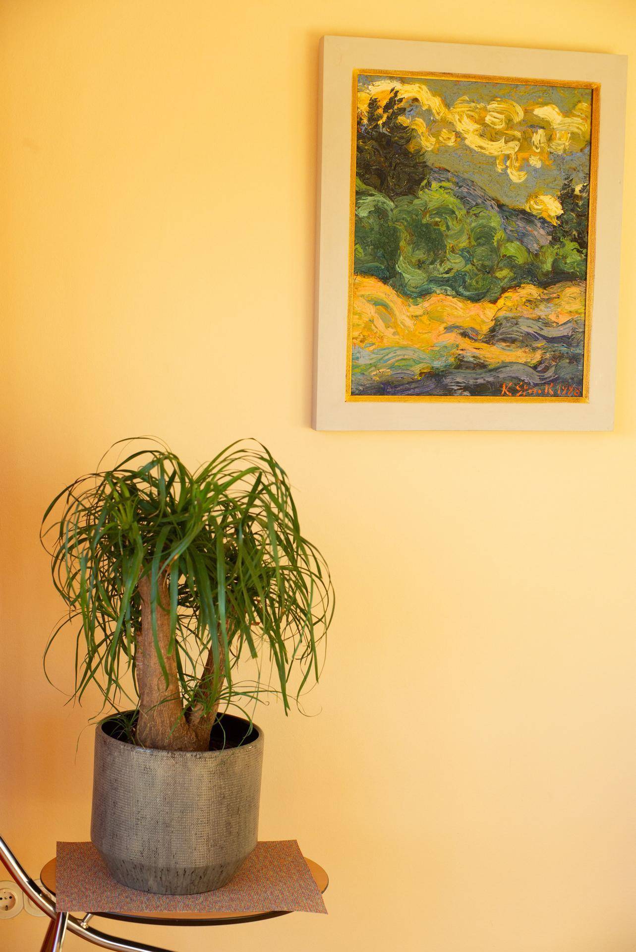 Dekorative Pflanze und ein farbenfrohes Gemälde an der hellen Wand des Esszimmers.