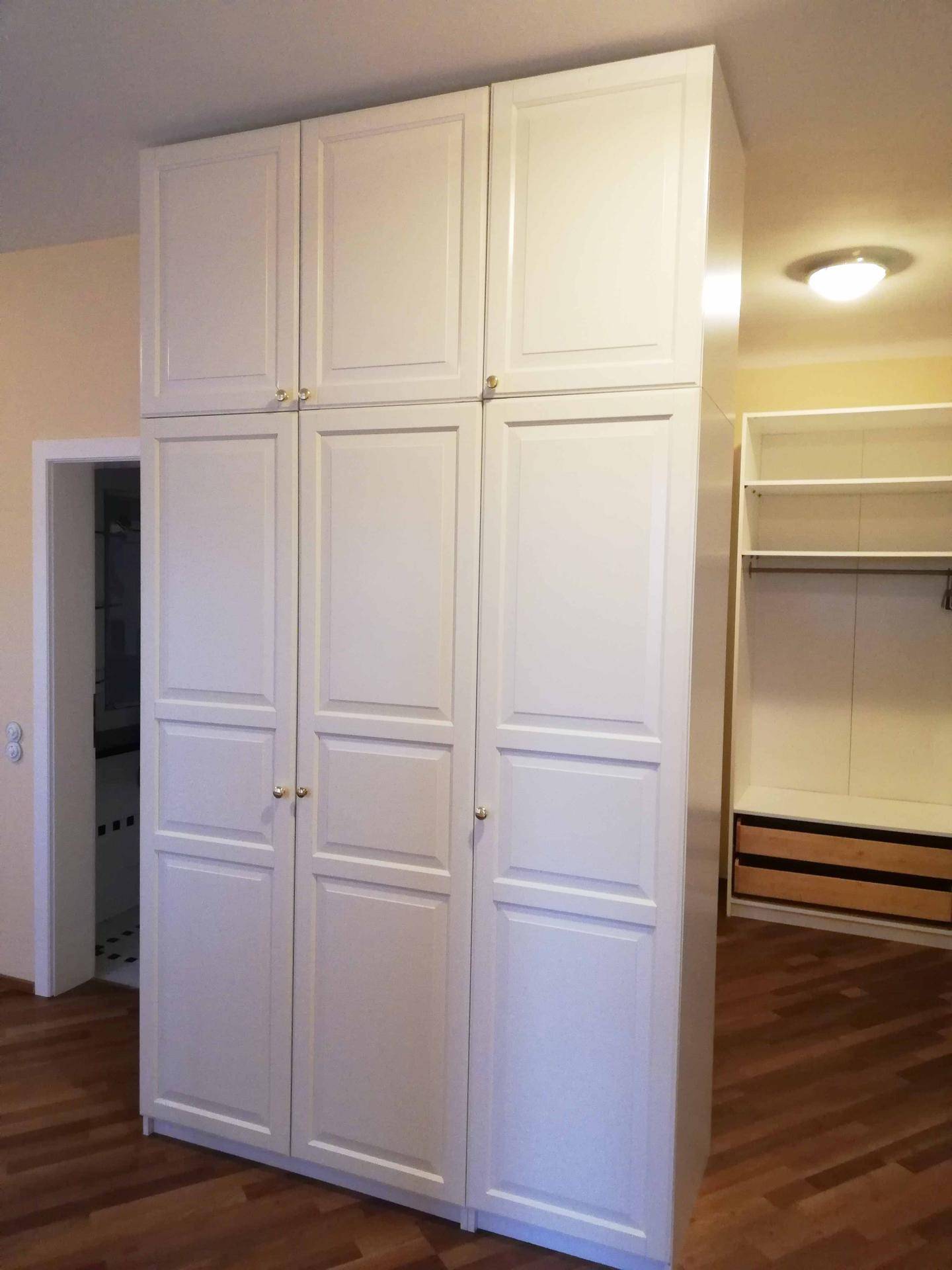 Schlafzimmer mit großen weißen Kleiderschränken und Holzfußboden.
