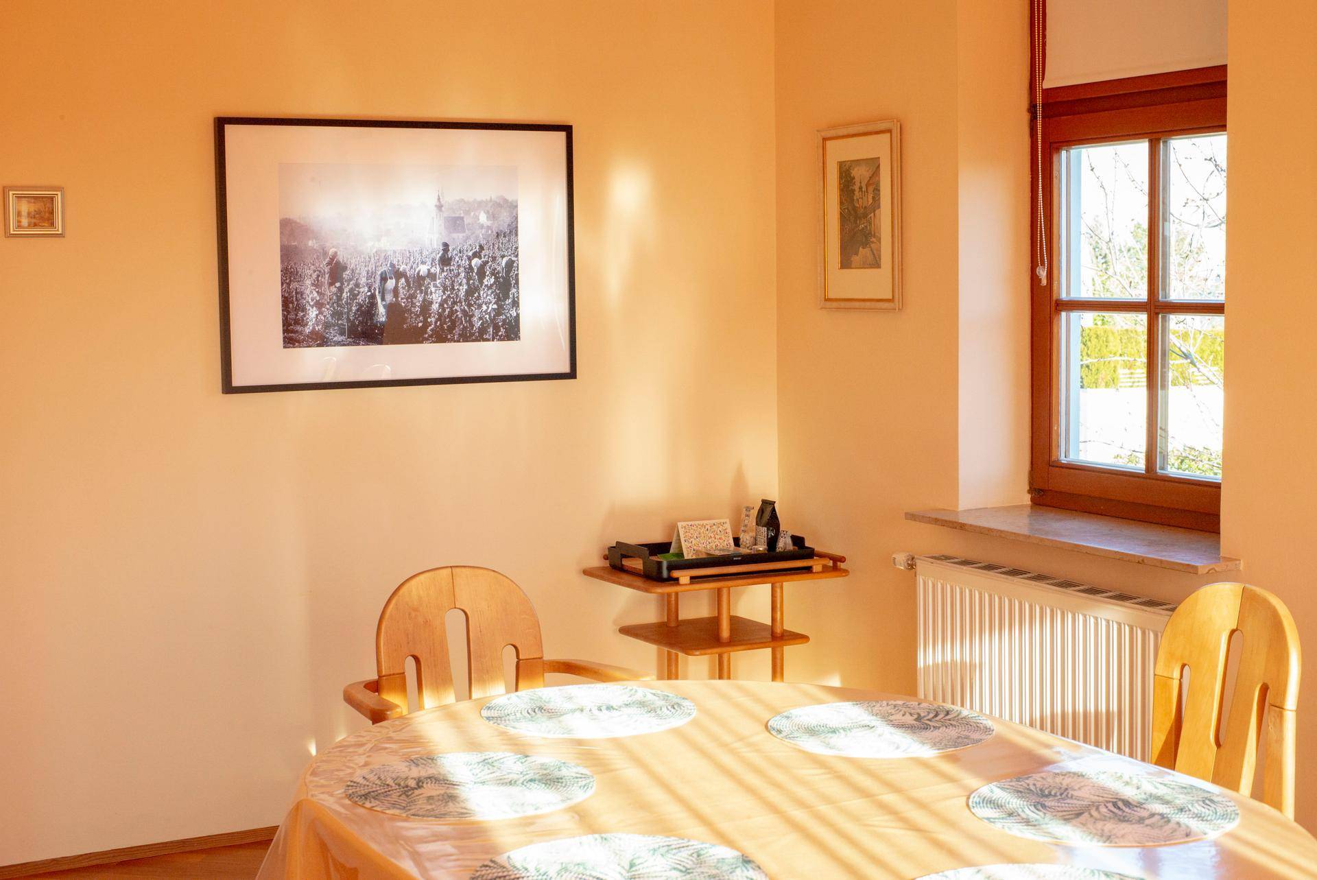 Heller Essbereich mit Holztisch, Stühlen und einem Fenster, das viel Tageslicht hereinlässt.