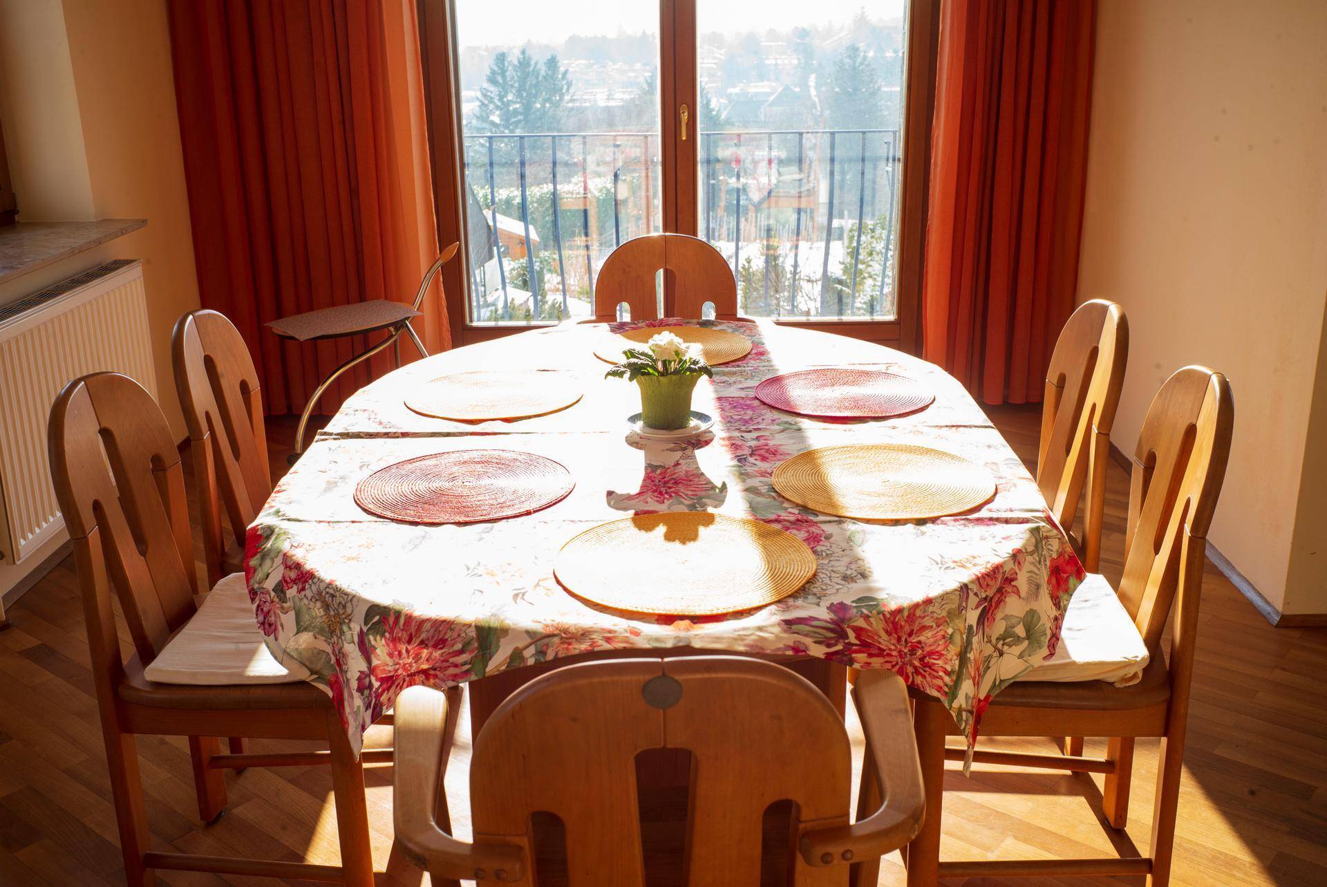 Essbereich mit gedecktem Tisch, Holzstühlen und Zugang zu einem Balkon mit Aussicht.