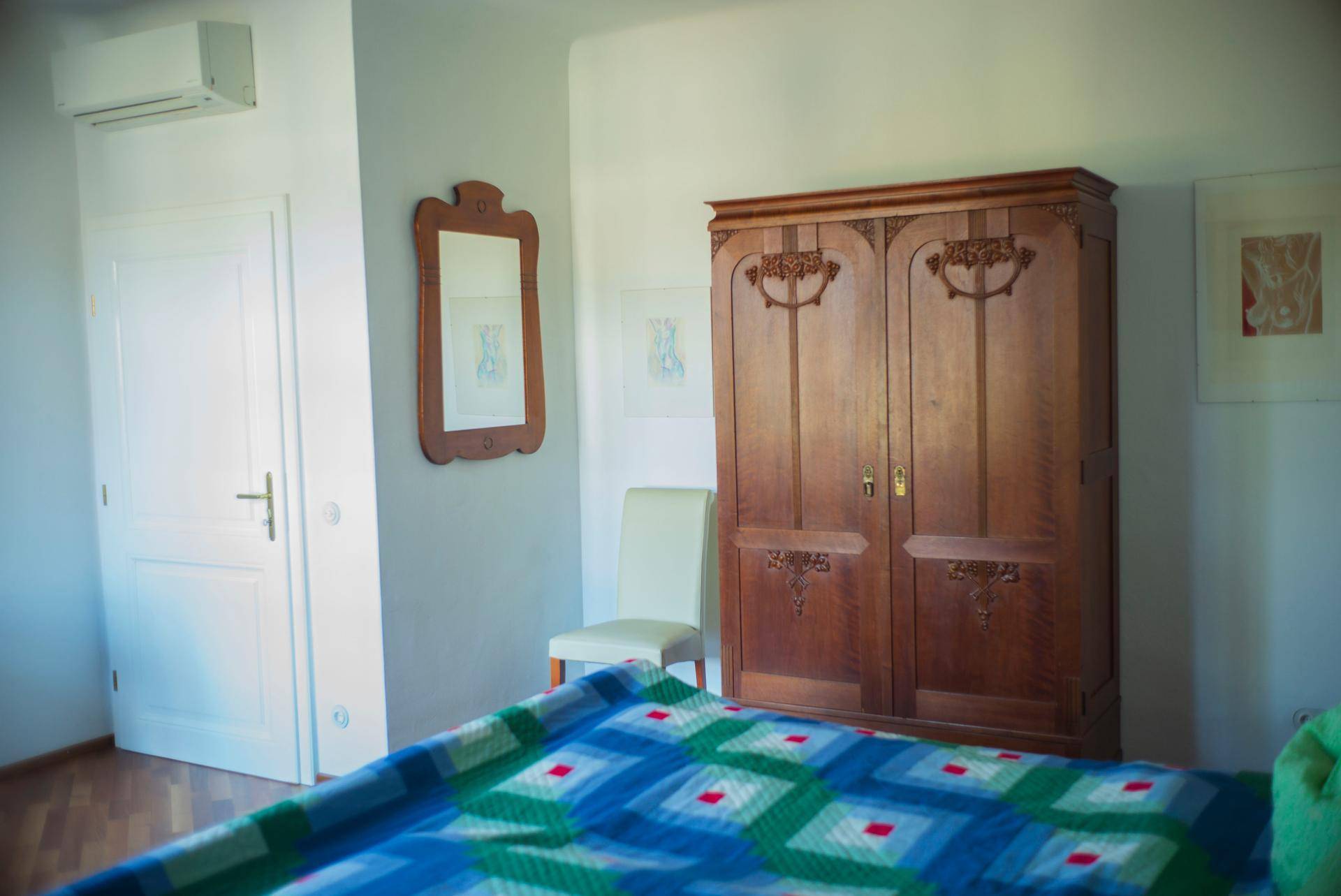 Geräumiges Schlafzimmer mit großem Holzschrank, Spiegel und Klimaanlage.