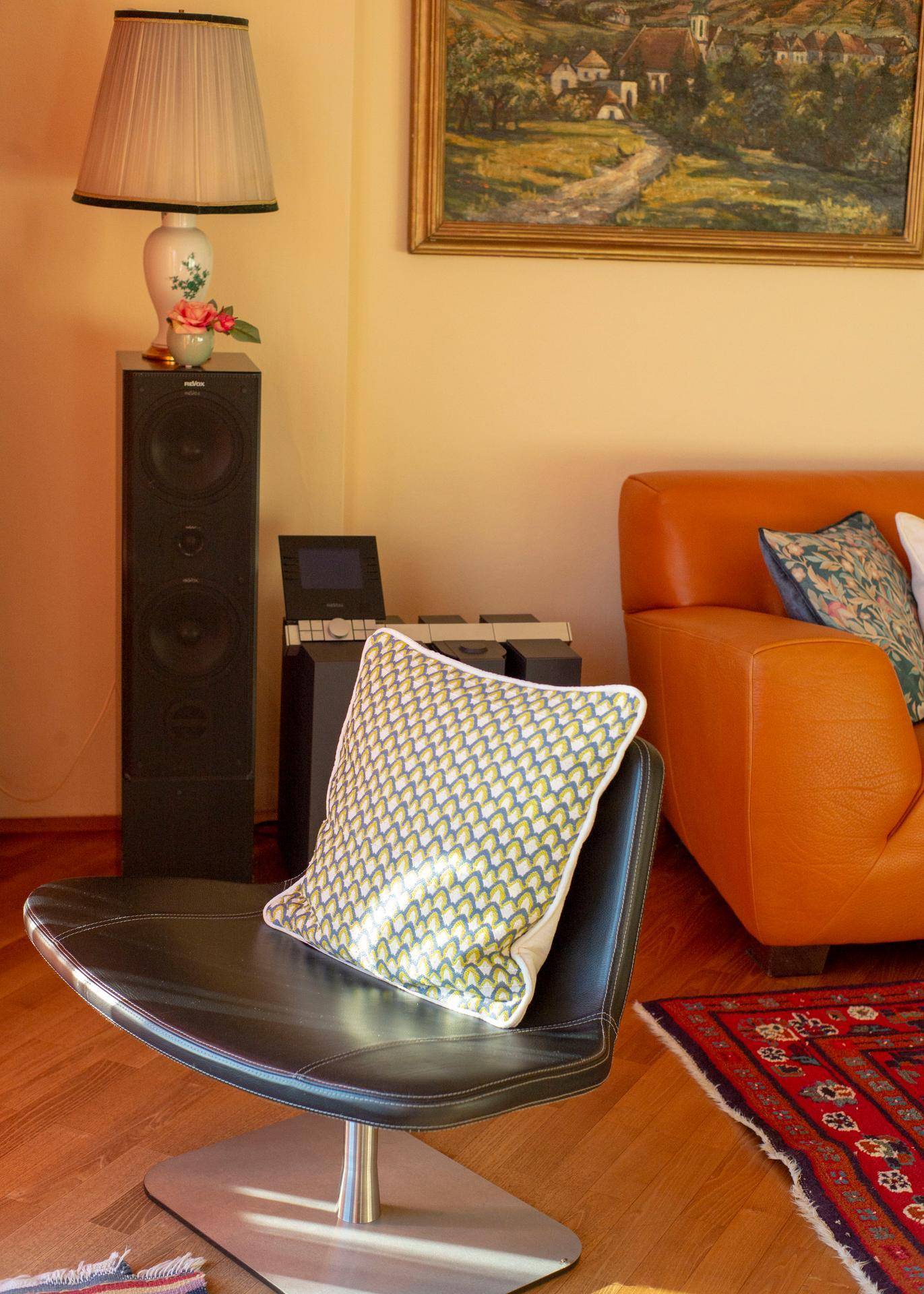 Gemütliche Sitzecke im Wohnzimmer mit Ledersessel, Teppich und Kunstwerk an der Wand.