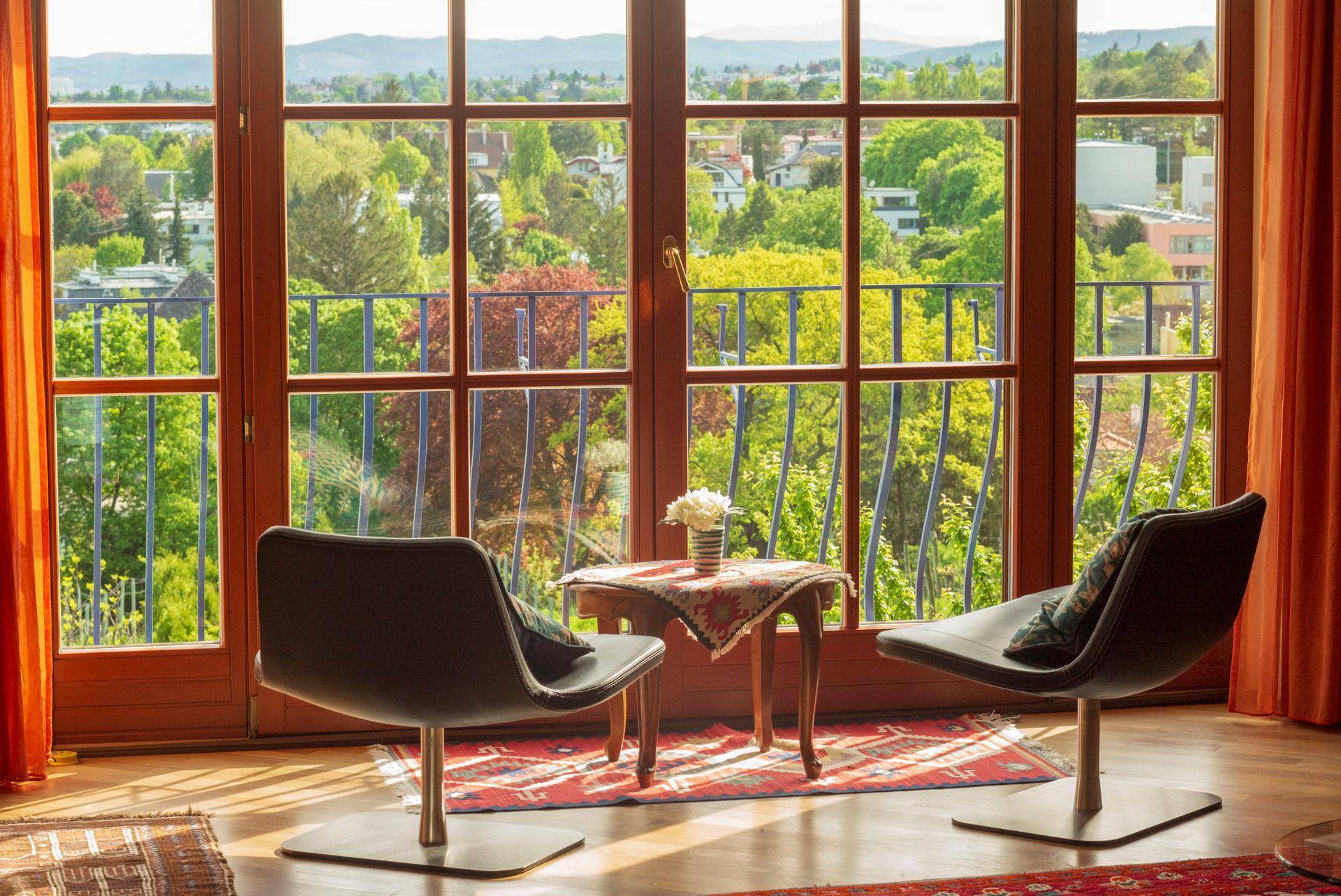 Wohnzimmer mit zwei modernen Sesseln vor einem großen Fenster mit Blick auf grüne Bäume.