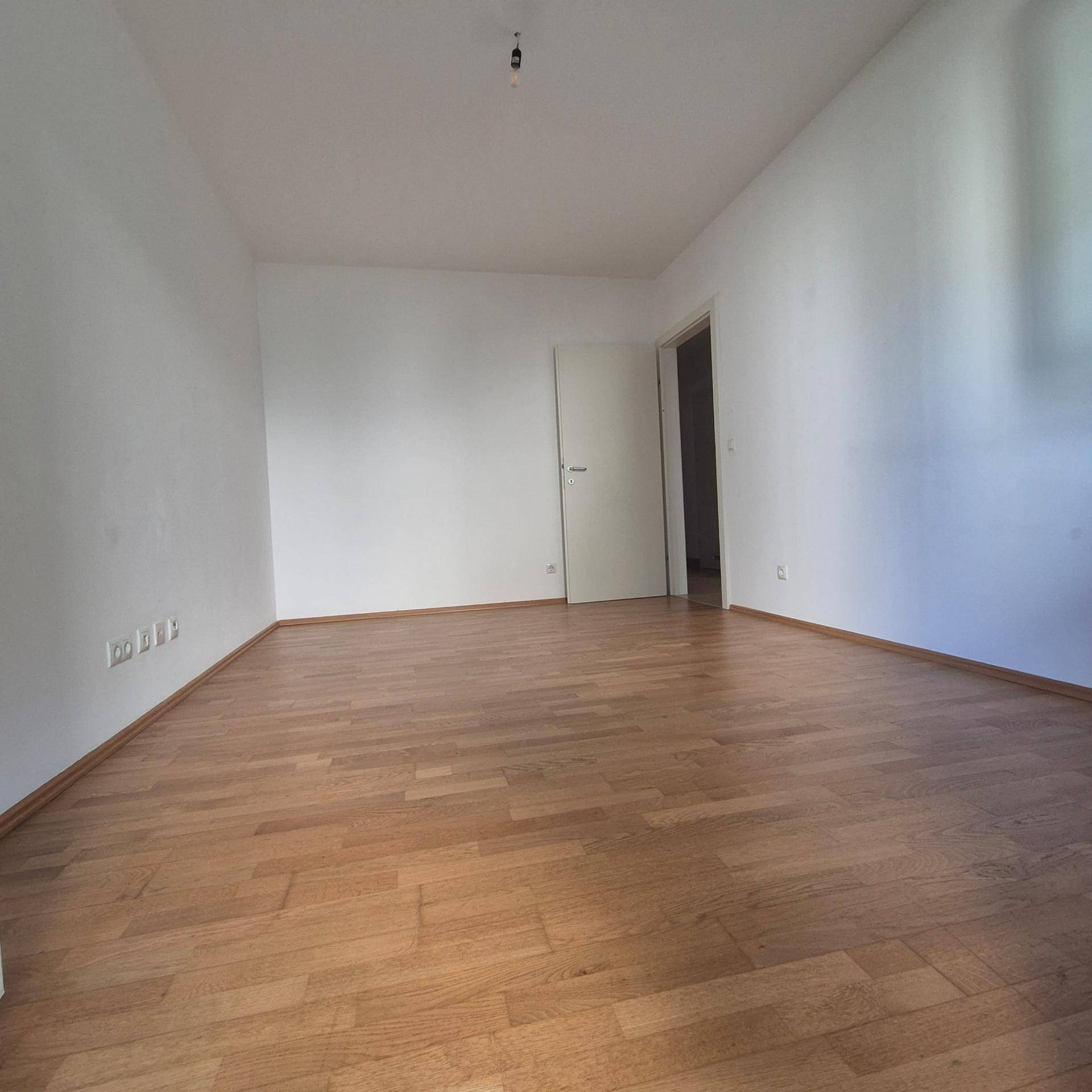 Leeres Zimmer mit hellem Parkettboden und weißen Wänden, bereit zur individuellen Gestaltung.