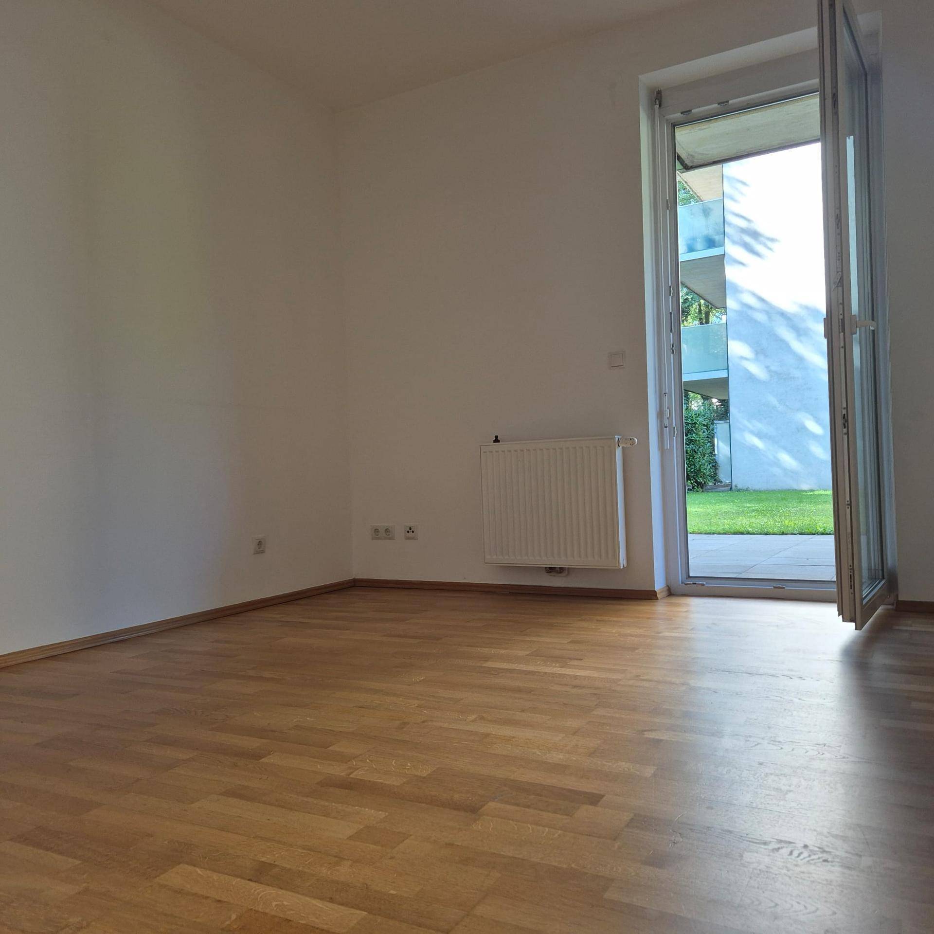Helles Zimmer mit Parkettboden und direktem Zugang zu einem Außenbereich.