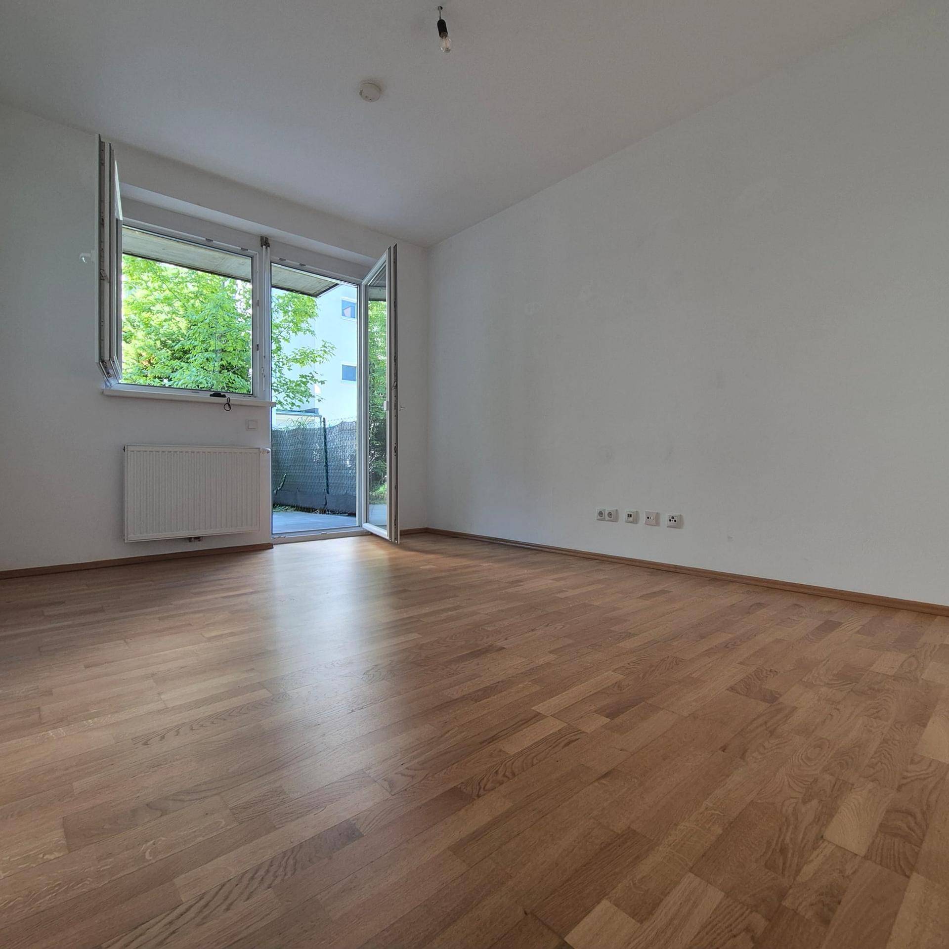 Geräumiges Zimmer mit Parkettboden und großer Fensterfront zum Außenbereich.