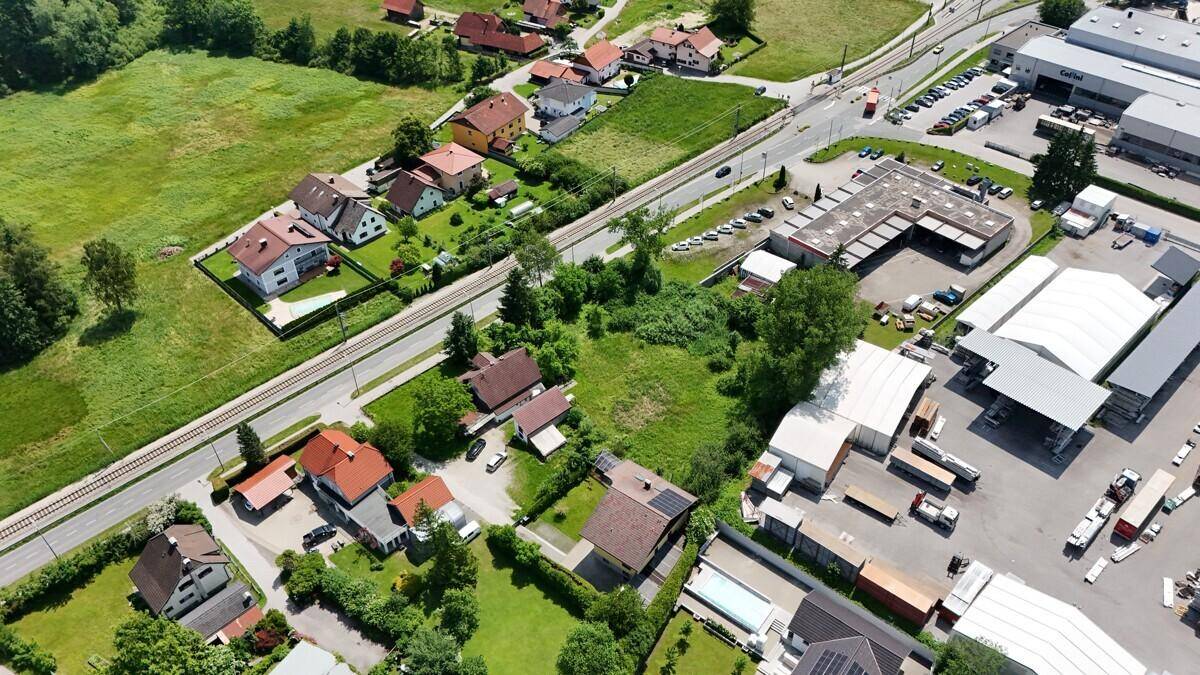 Panoramablick aus der Vogelperspektive auf eine Siedlung mit angrenzenden Gewerbeflächen und Feldern.