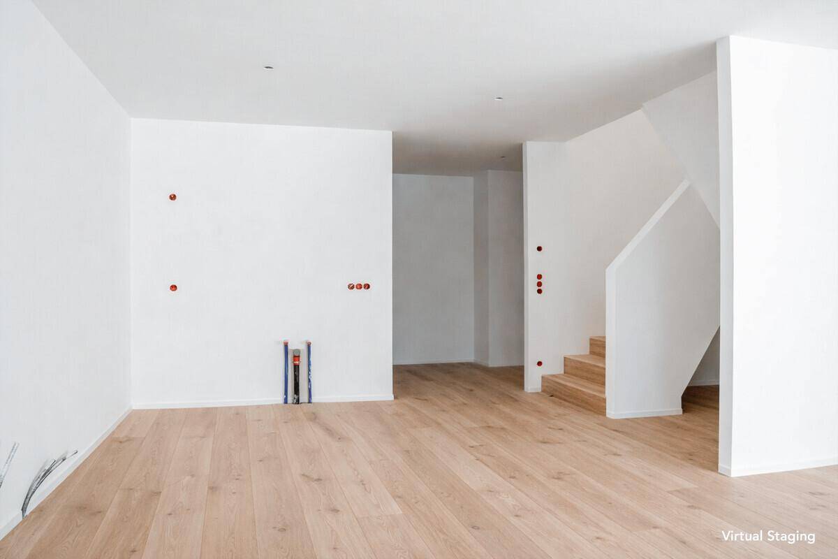 Modern inszenierter Wohnbereich mit hellem Holzboden und offener Treppe im Hintergrund.
