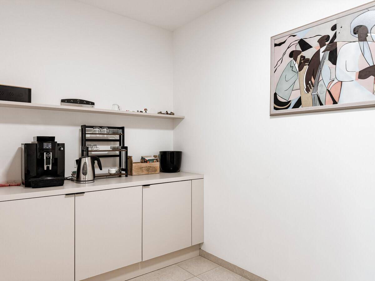 Kleine Küchenzeile mit Kaffeemaschine und minimalistischen Schränken.