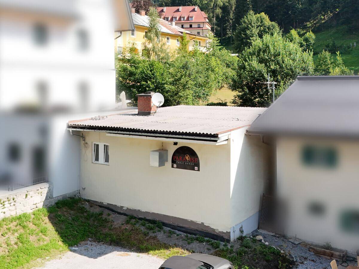 Rückansicht des Geschäftsgebäudes mit Flachdach, Schornstein und Satellitenschüssel.