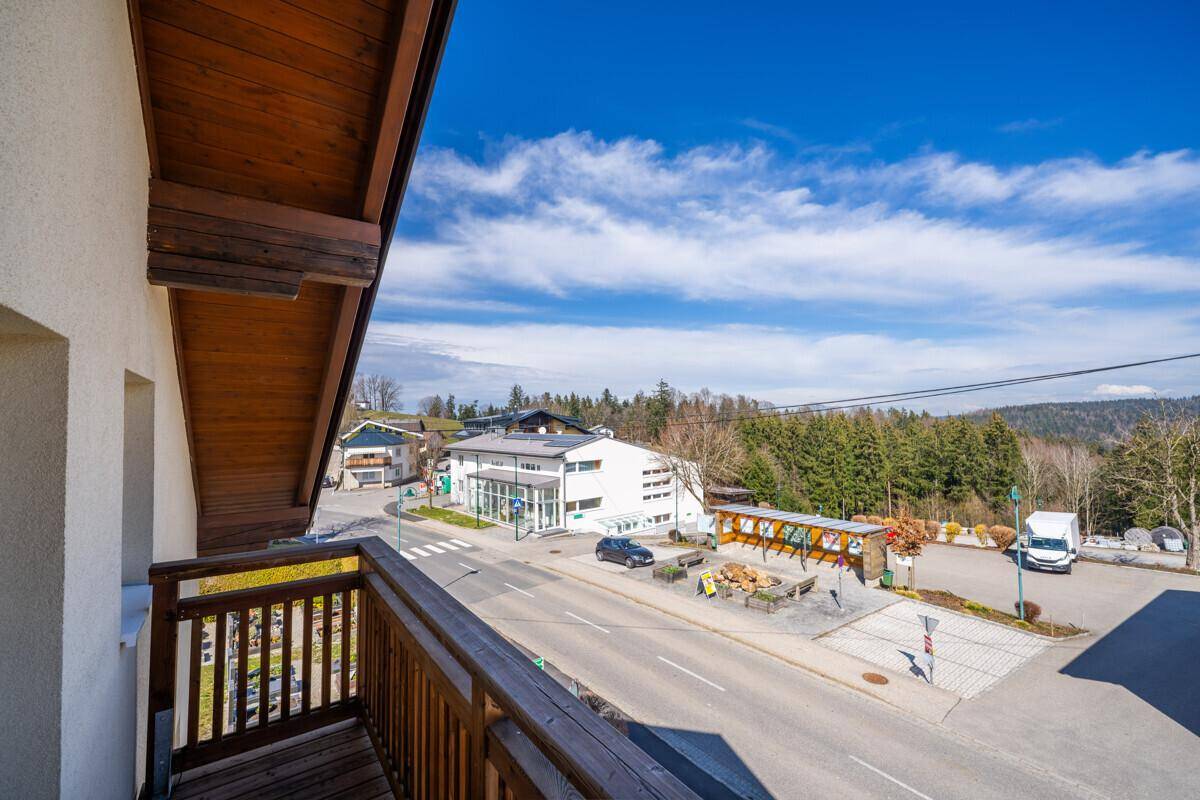 Blick vom Balkon auf die umliegende Landschaft und die Straße mit weiteren Gebäuden.