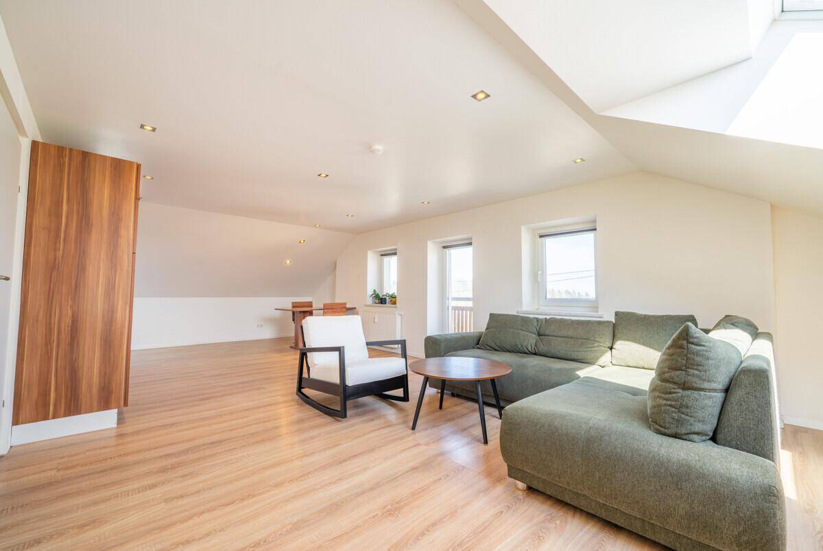 Helles Wohnzimmer im Dachgeschoss mit Holzboden, gemütlicher Sitzecke und Dachfenster.