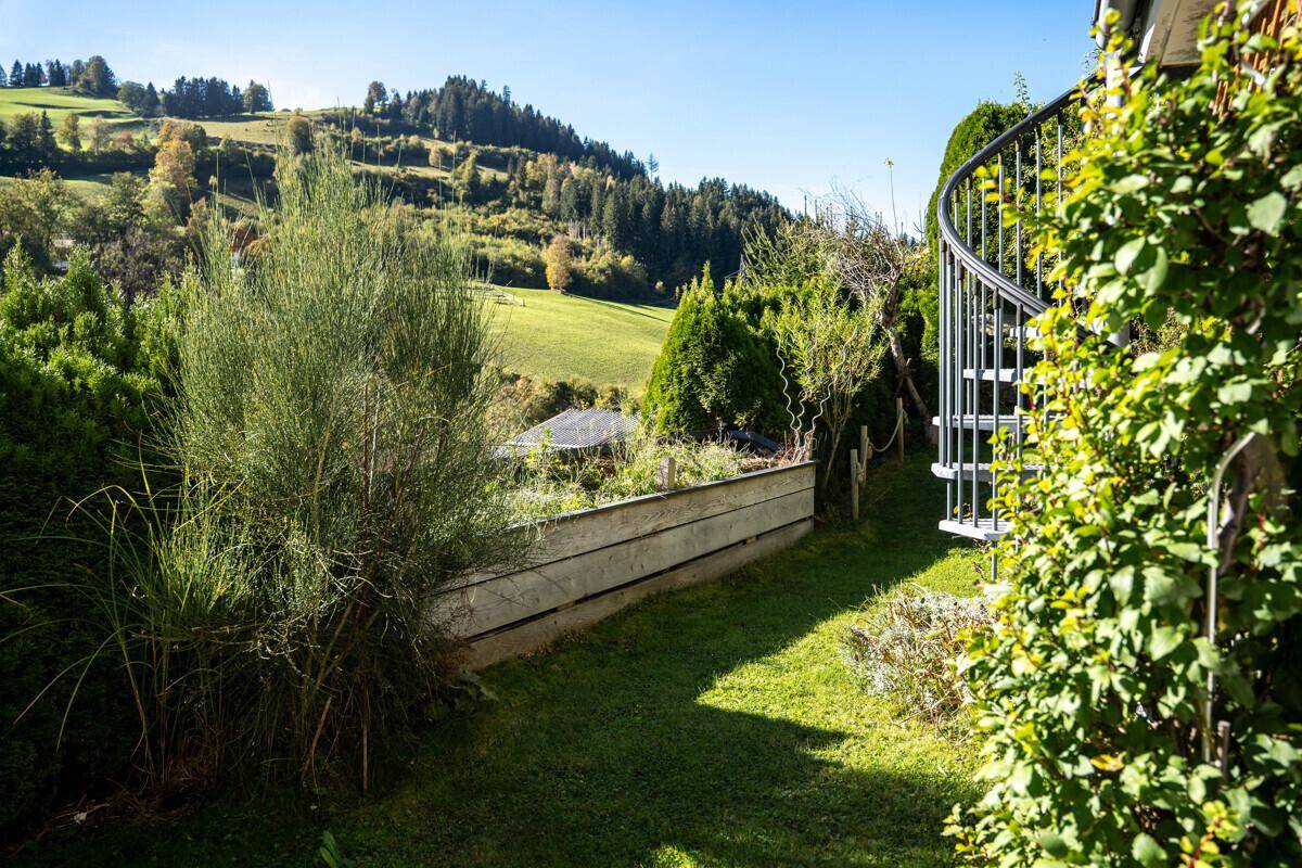 Gepflegter Gartenbereich mit einer Wendeltreppe und weitem Blick auf die grüne Hügellandschaft.