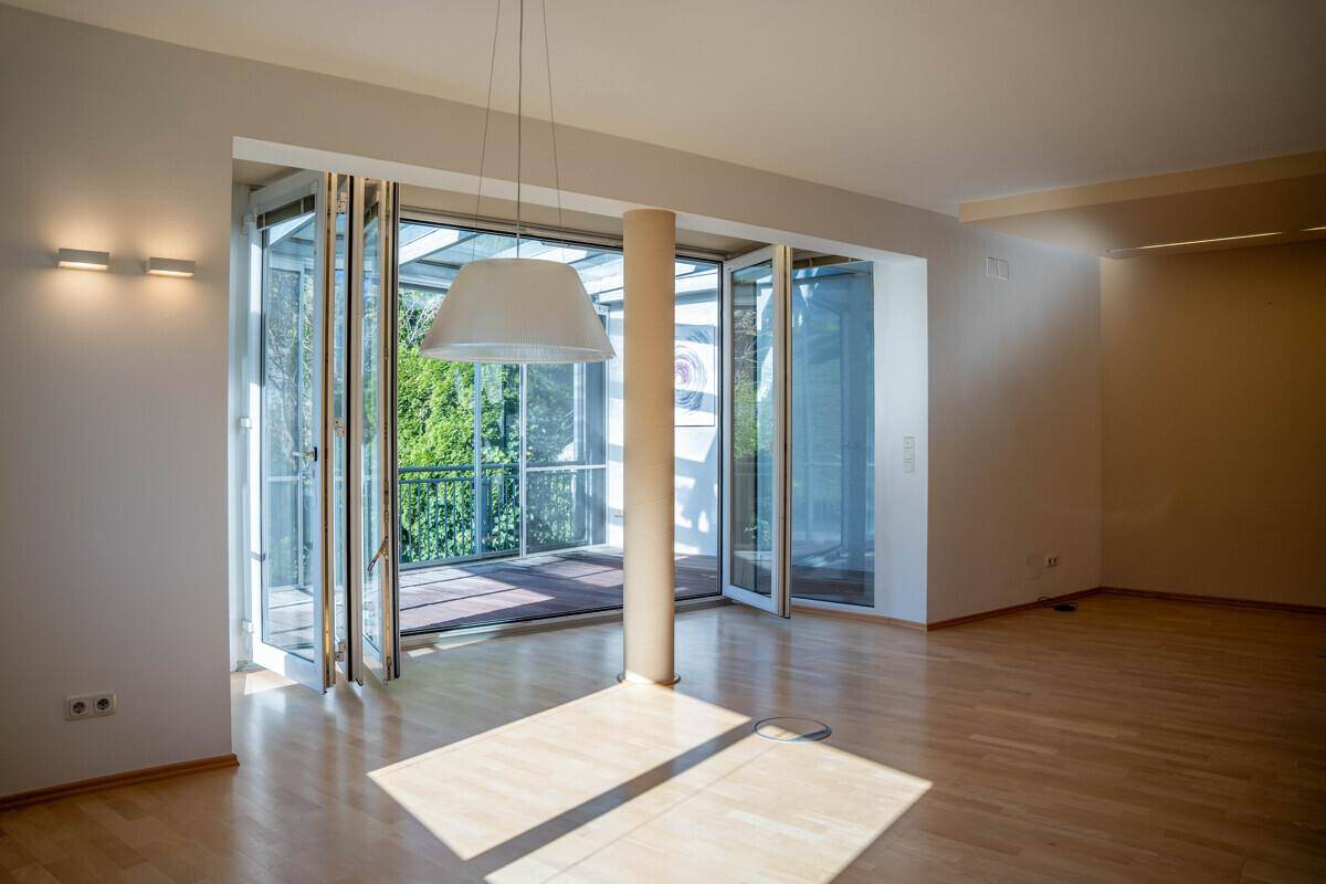 Helles Wohnzimmer mit Parkettboden und großen Falttüren, die zu einem Balkon führen.