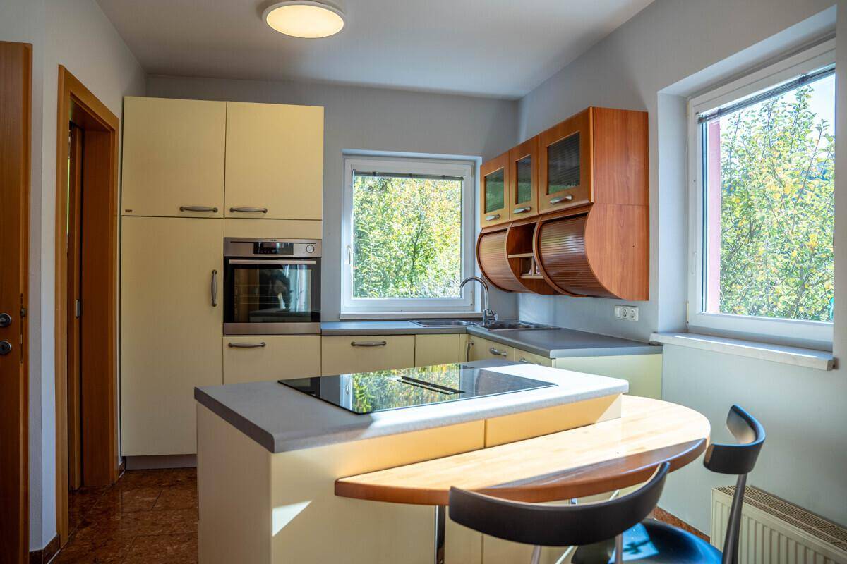 Funktionale Küche mit hellen Schränken, integriertem Backofen und Kochfeld mit Frühstücksbar.