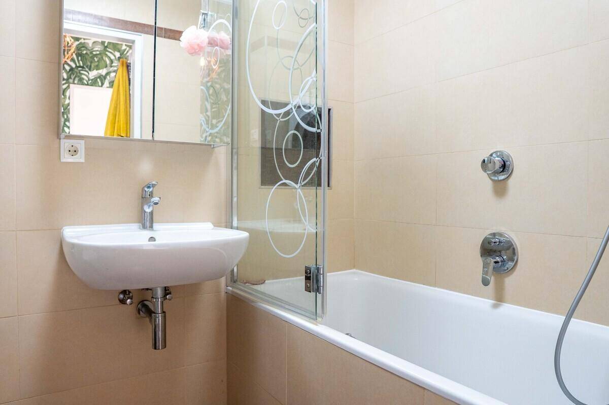 Modernes Badezimmer mit Badewanne, Duschwand und Waschbecken.