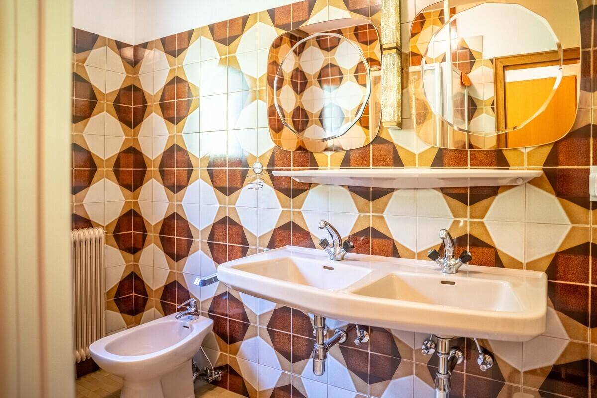 Badezimmer mit auffälligen braun-weißen Fliesen, Doppelwaschbecken und Bidet.