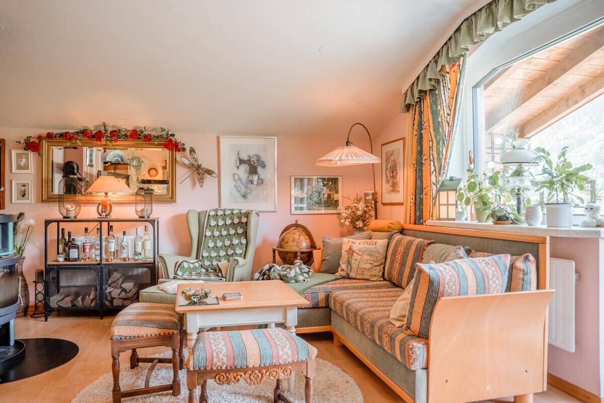 Geräumiges Wohnzimmer mit Ecksofa, Holzboden und Blick auf die umliegende Landschaft.