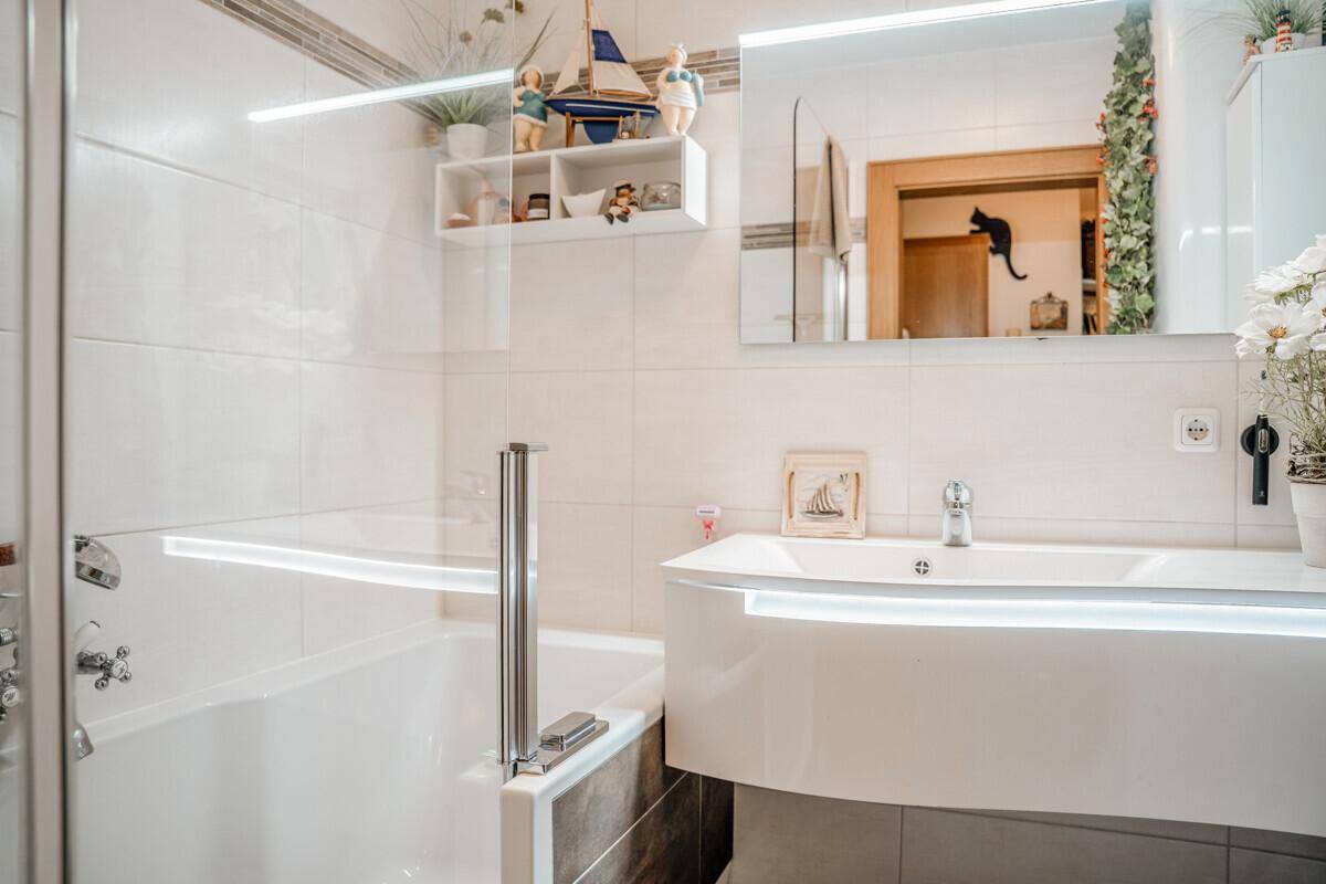 Modernes Badezimmer mit Badewanne, Einzelwaschbecken und hellen Fliesen.