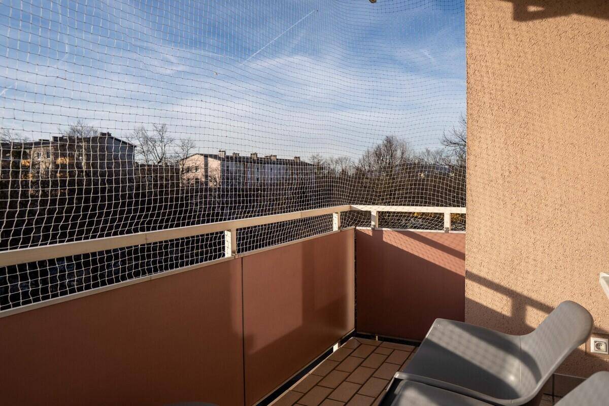 Balkon mit Schutznetz, Fliesenboden und Blick auf die umliegenden Gebäude.