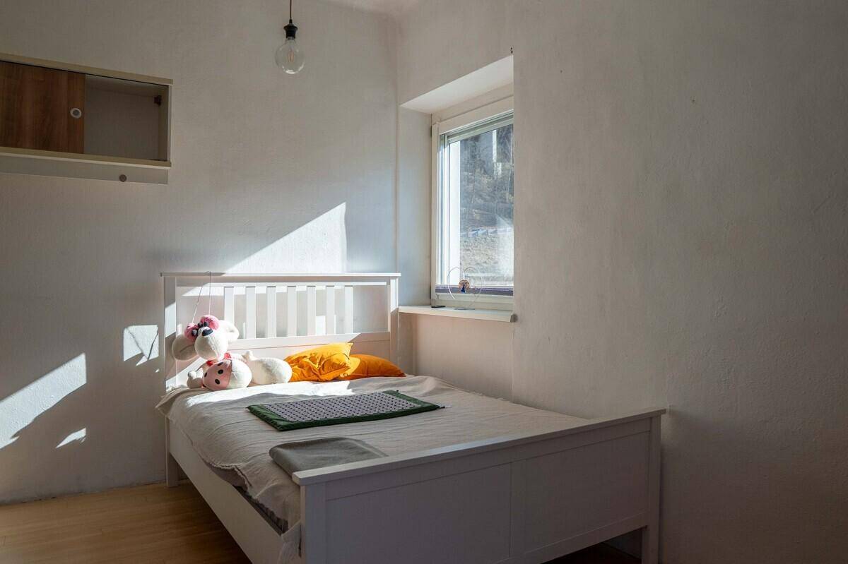 Helles Kinderzimmer mit weißem Bett, Holzboden und viel natürlichem Licht.