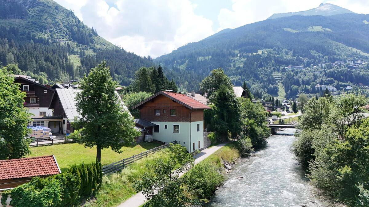 Panoramablick auf das Haus am Fluss in einer malerischen Berglandschaft mit viel Grün.