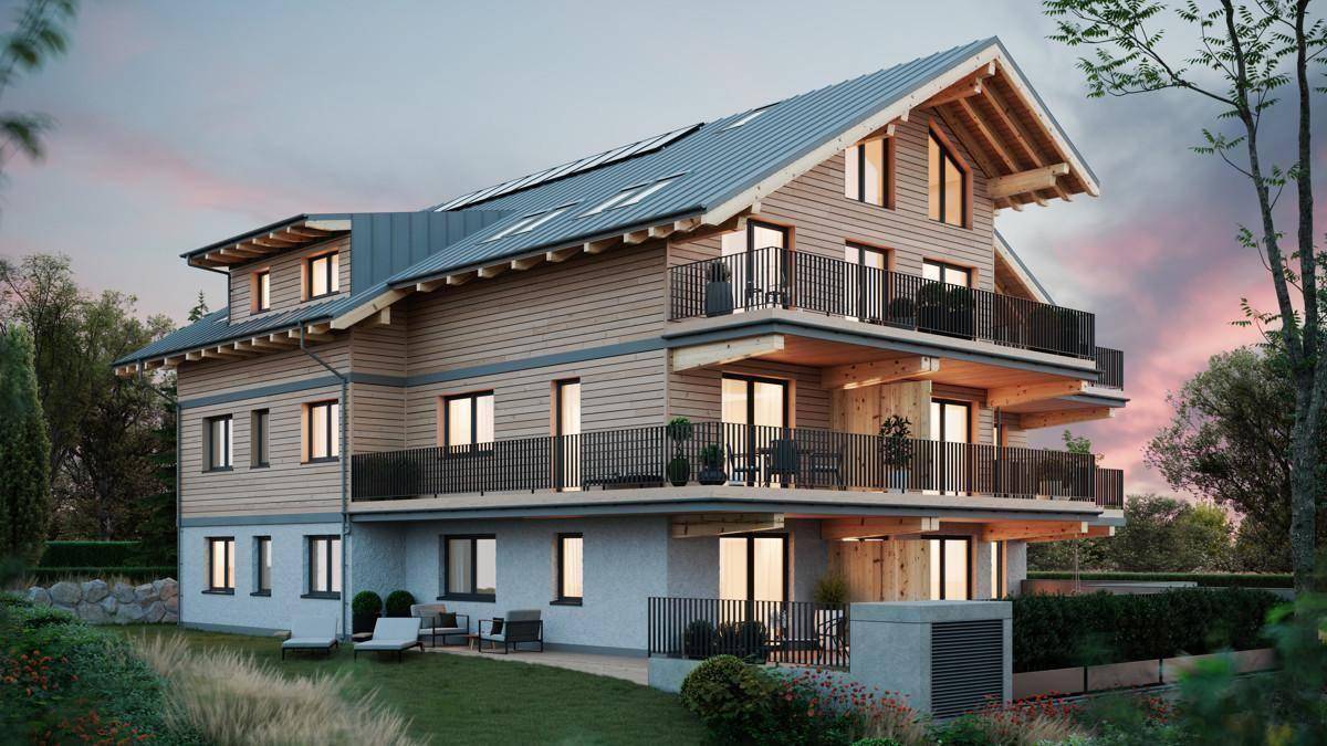 Modernes Mehrfamilienhaus im alpinen Stil mit Holzfassade, Balkonen und Solarpaneelen auf dem Dach.