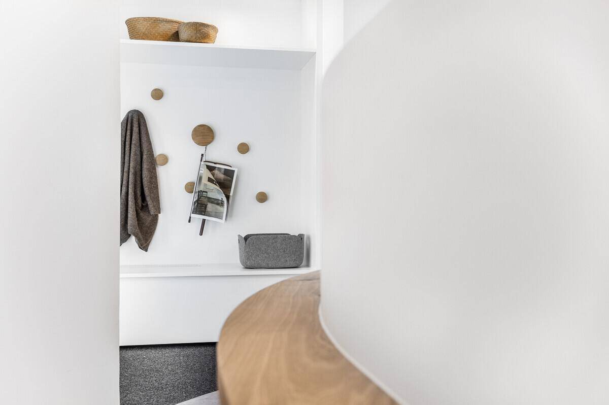 Detailansicht eines modernen Garderobenbereichs mit runden Holzhaken und Ablageflächen, minimalistisch und praktisch.