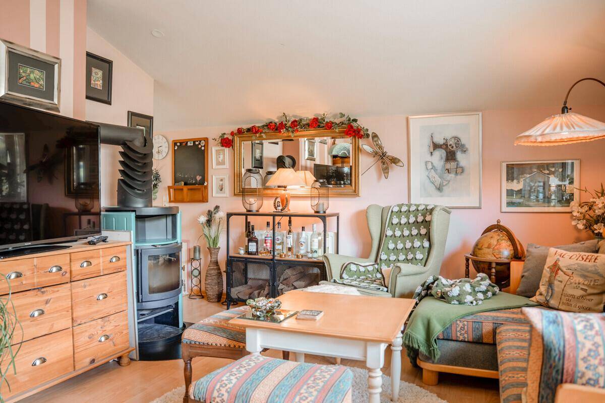 Gemütliches Wohnzimmer mit Kaminofen, Holzboden und traditioneller Einrichtung.