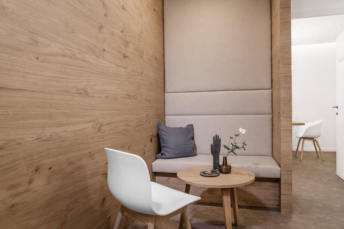Detailansicht einer Sitznische im Wartebereich mit Holzwand und gepolsterter Bank, modern und komfortabel.