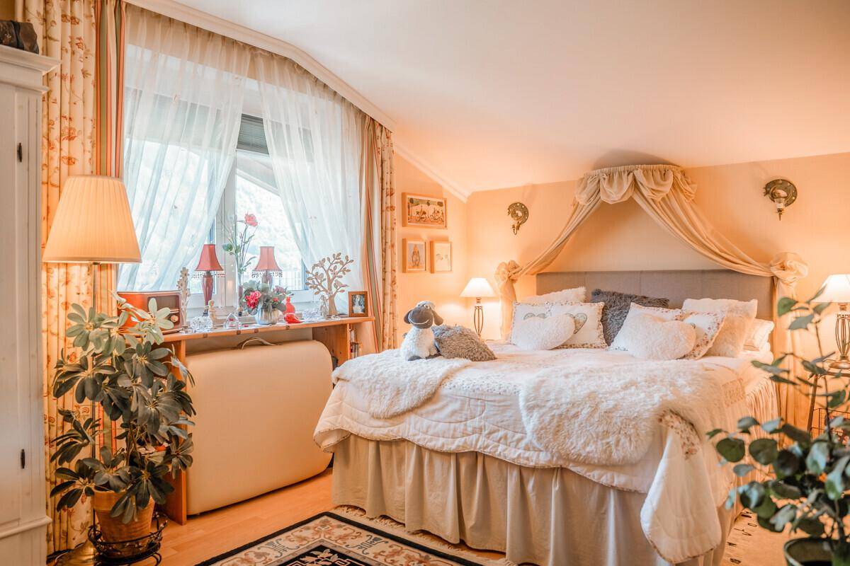 Romantisches Schlafzimmer mit Himmelbett, Holzboden und viel Tageslicht.