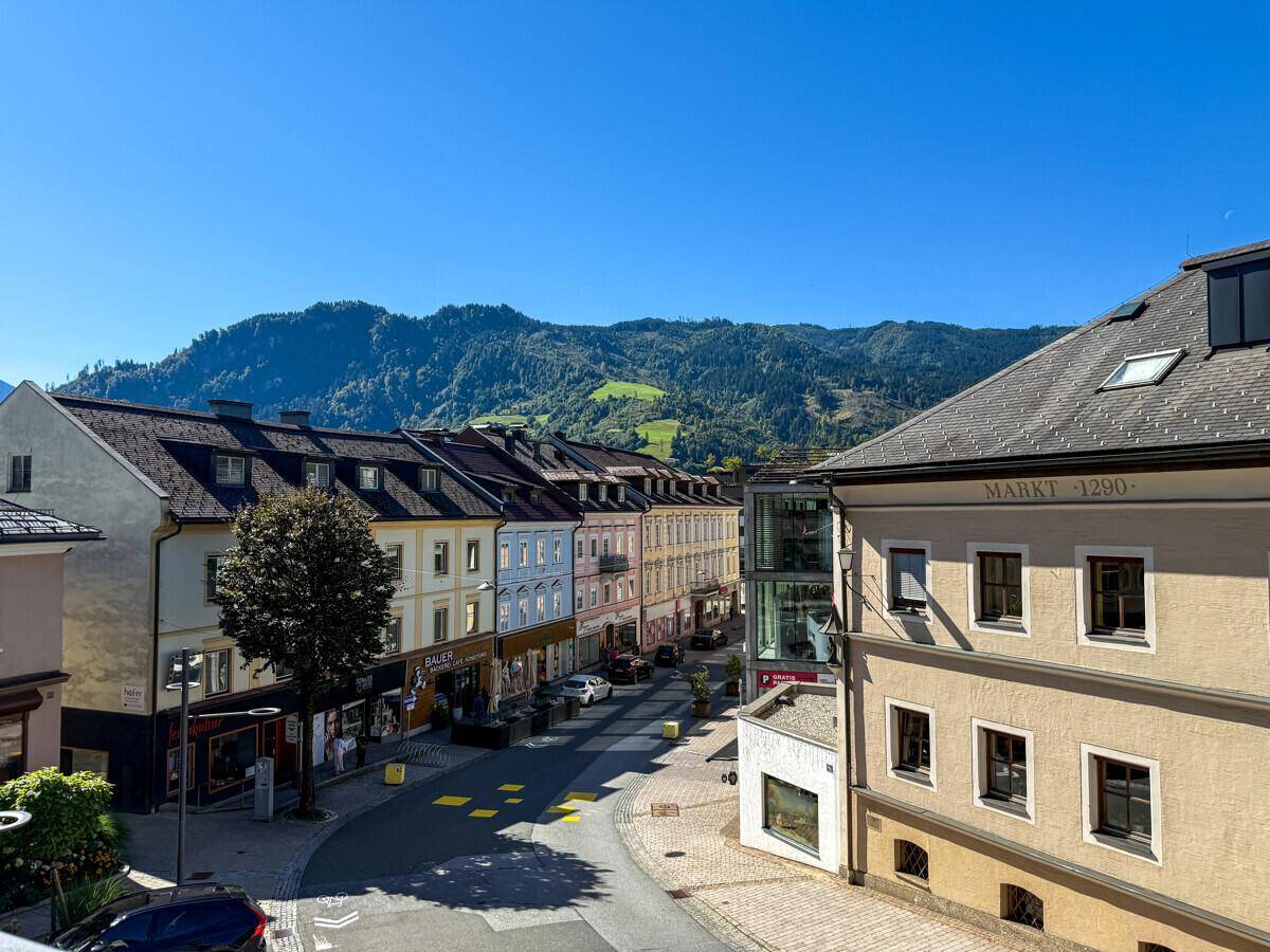 Panoramablick auf die historische Stadtstraße mit bunten Gebäuden und majestätischen Bergen.
