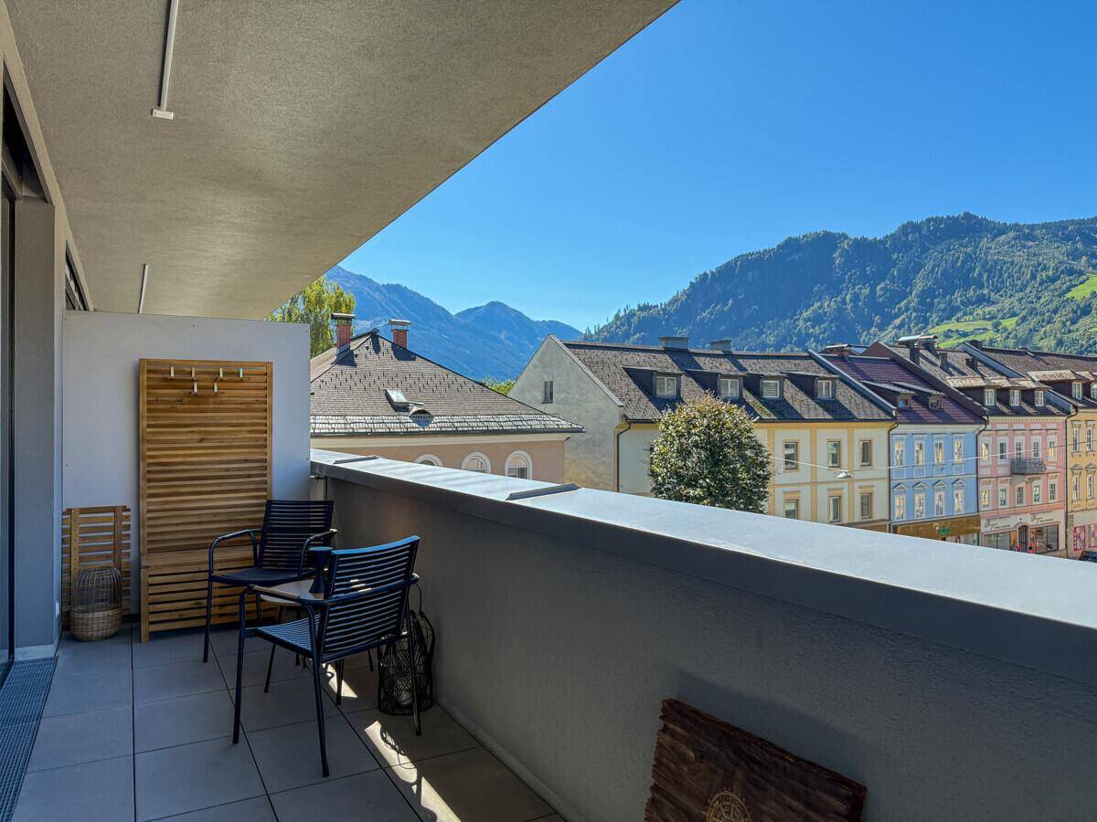 Sonniger Balkon mit Sitzgelegenheiten, Bergblick und Blick auf die Altstadt.