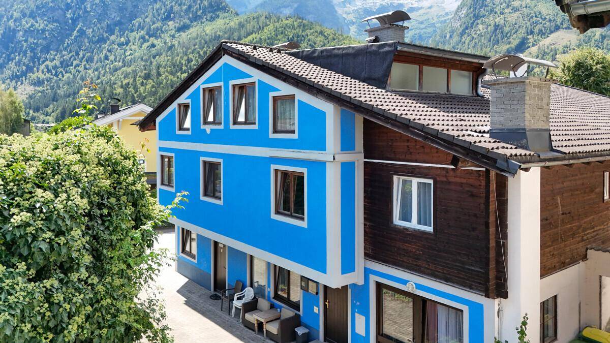 Attraktives Gebäude mit blauer Fassade, Holzelementen und Satteldach in alpiner Umgebung.