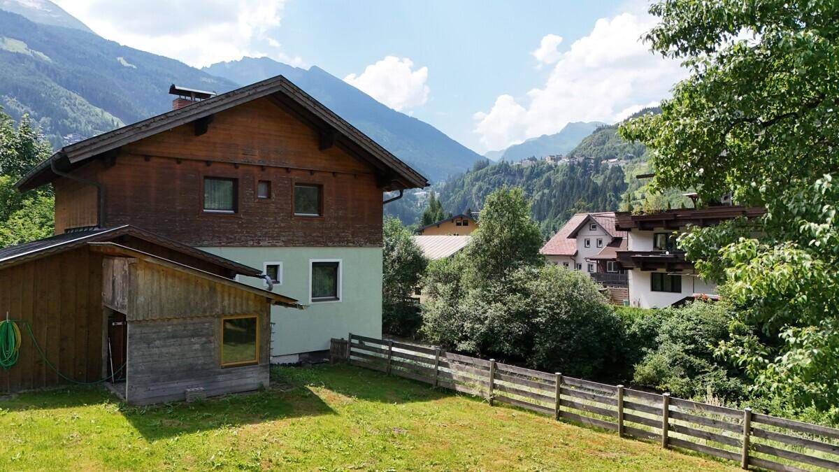 Rückseite des Hauses mit Garten und Blick auf die umliegenden Berge und Wälder.