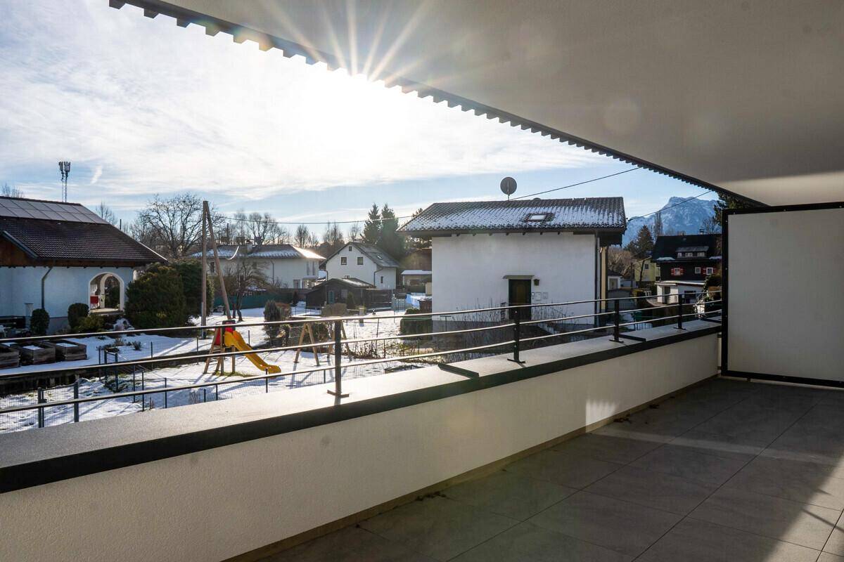 Sonniger Balkon mit Fliesenboden und Blick auf die verschneite Nachbarschaft und Berge.