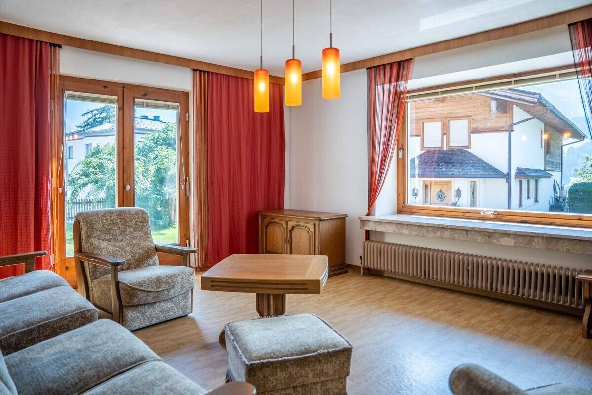 Gemütliches Wohnzimmer mit Holzmöbeln, Parkettboden und Zugang zum Garten.