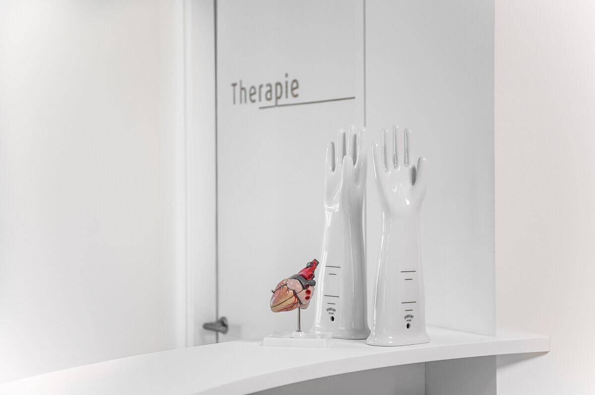 Detail der Rezeption mit "Therapie"-Beschriftung an der Tür und medizinischen Dekorationsgegenständen, sauber und professionell.
