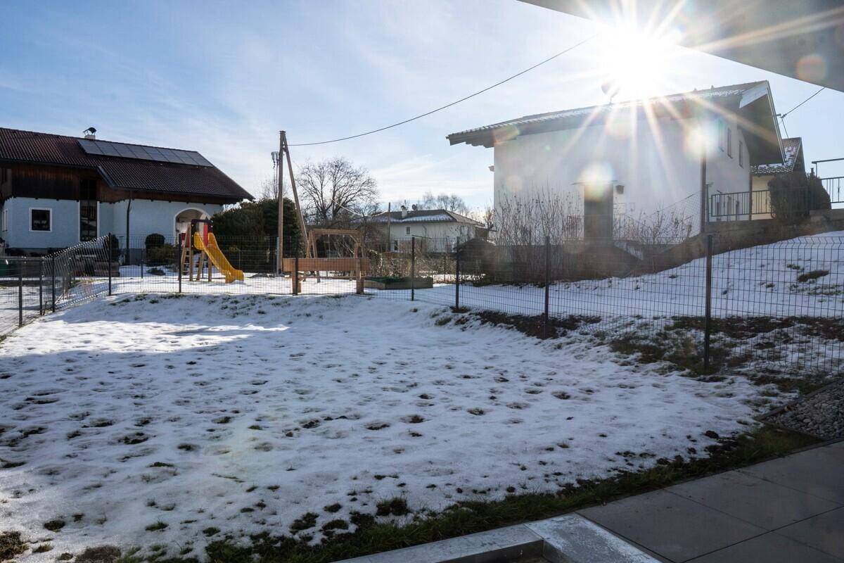 Verschneiter Gemeinschaftsgarten mit Spielplatz und Sitzbank, ideal für Familien.