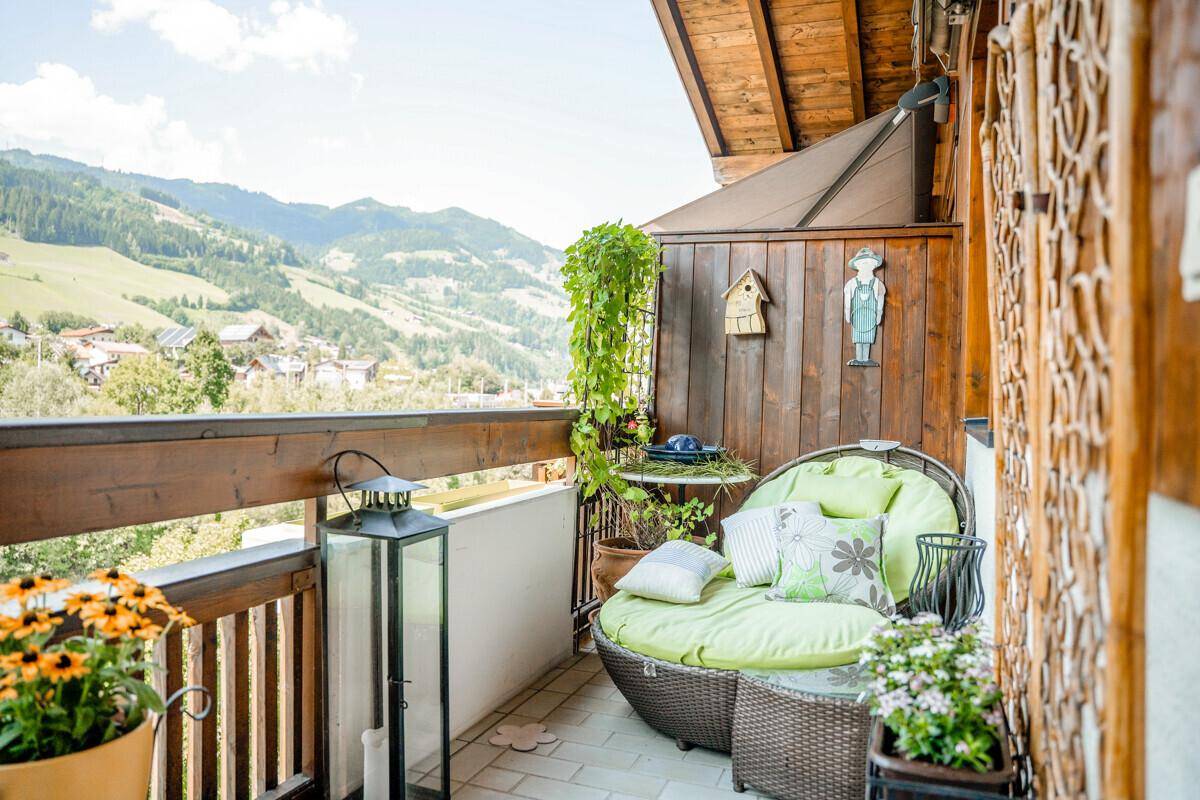 Sonniger Balkon mit bequemen Sitzgelegenheiten und Panoramablick auf die Berge.
