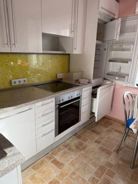 Moderne Küche mit integriertem Kühlschrank, Backofen und weißen Schränken.