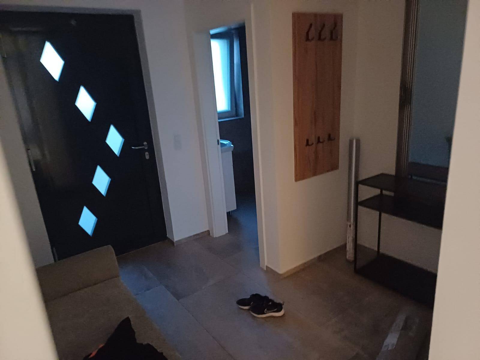 Heller Eingangsbereich mit moderner Haustür, Garderobe und Spiegel.